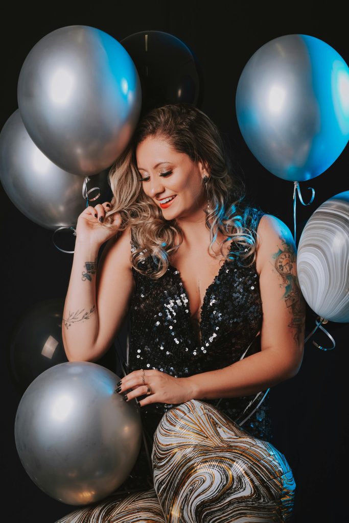 Woman smiling in a glamorous dress surrounded by balloons, ideal for fashion and celebration themes.