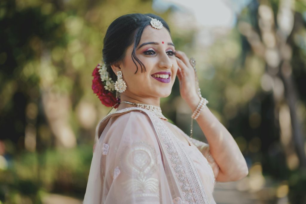 Smiling woman in traditional Indian attire with intricate jewelry outdoors.