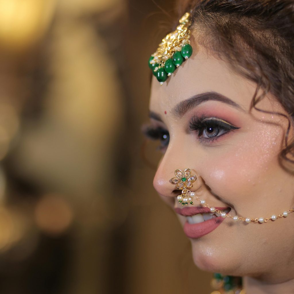 Close-up portrait of a smiling Indian bride with traditional jewelry and makeup.