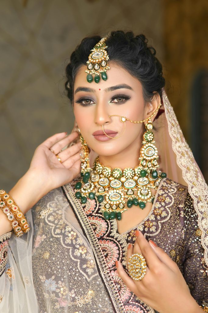 A bride adorned with traditional Indian jewelry and attire in a graceful pose.